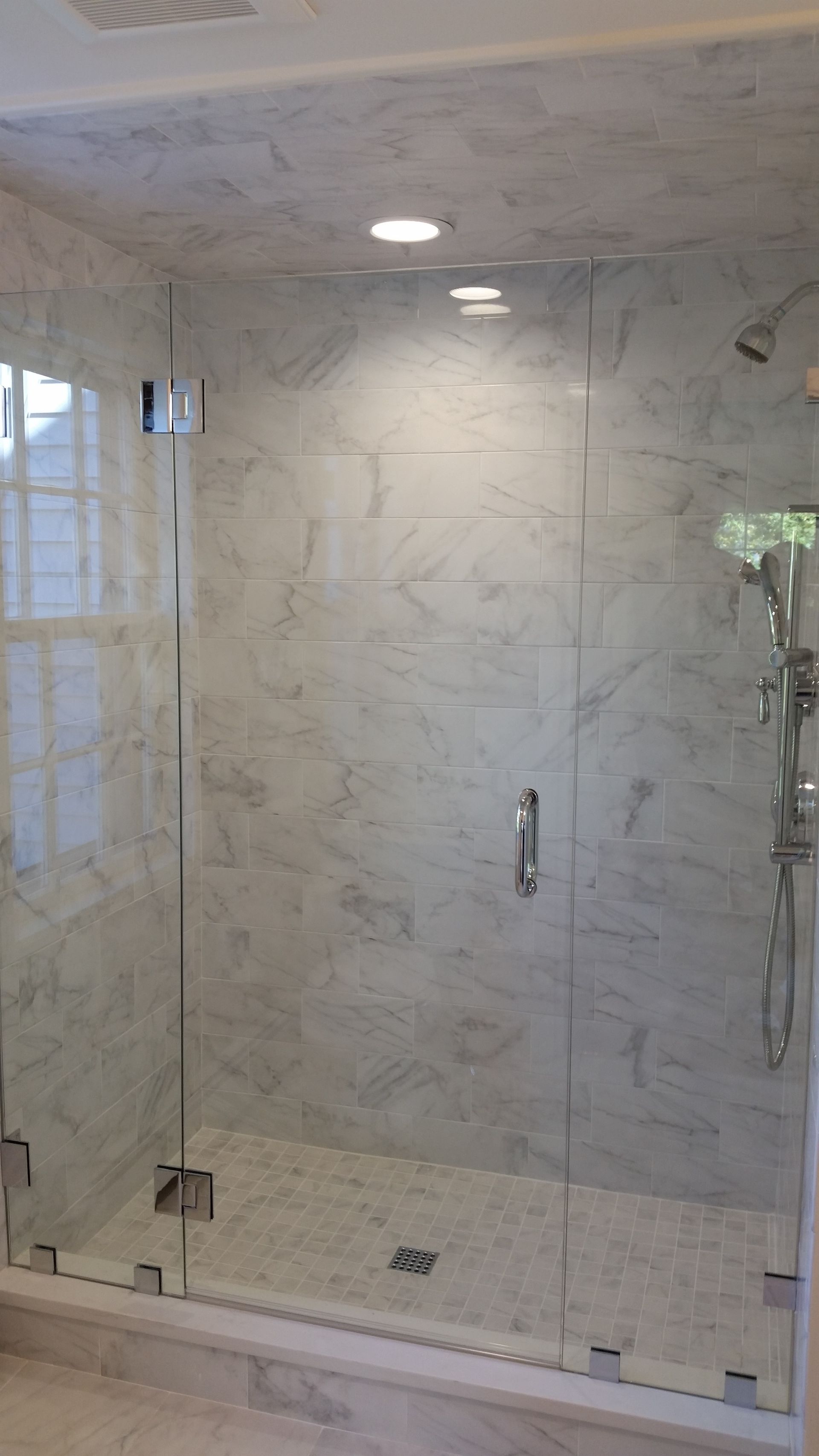 A bathroom with a walk in shower with a glass door.