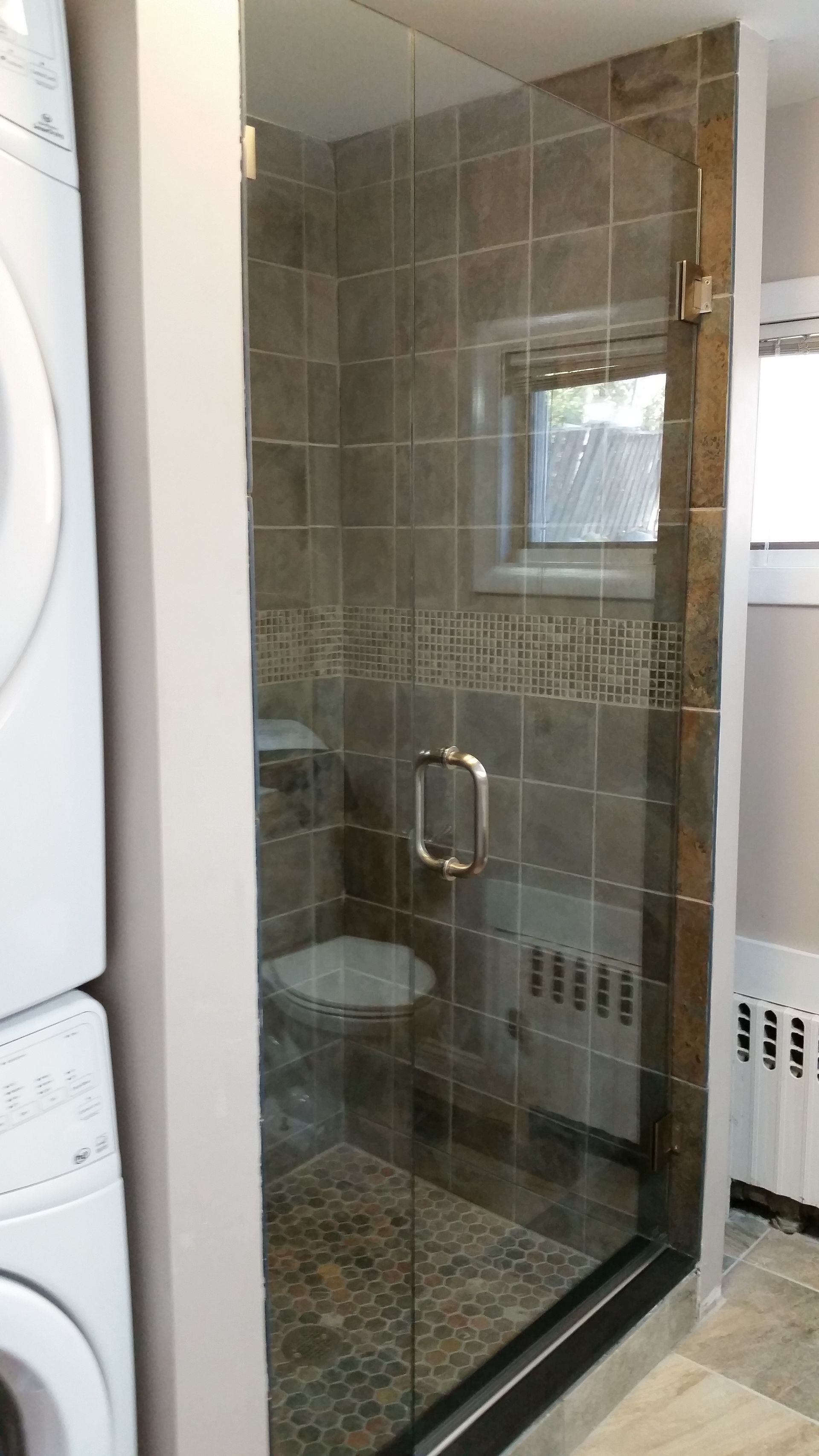 A bathroom with a glass shower door and a toilet.
