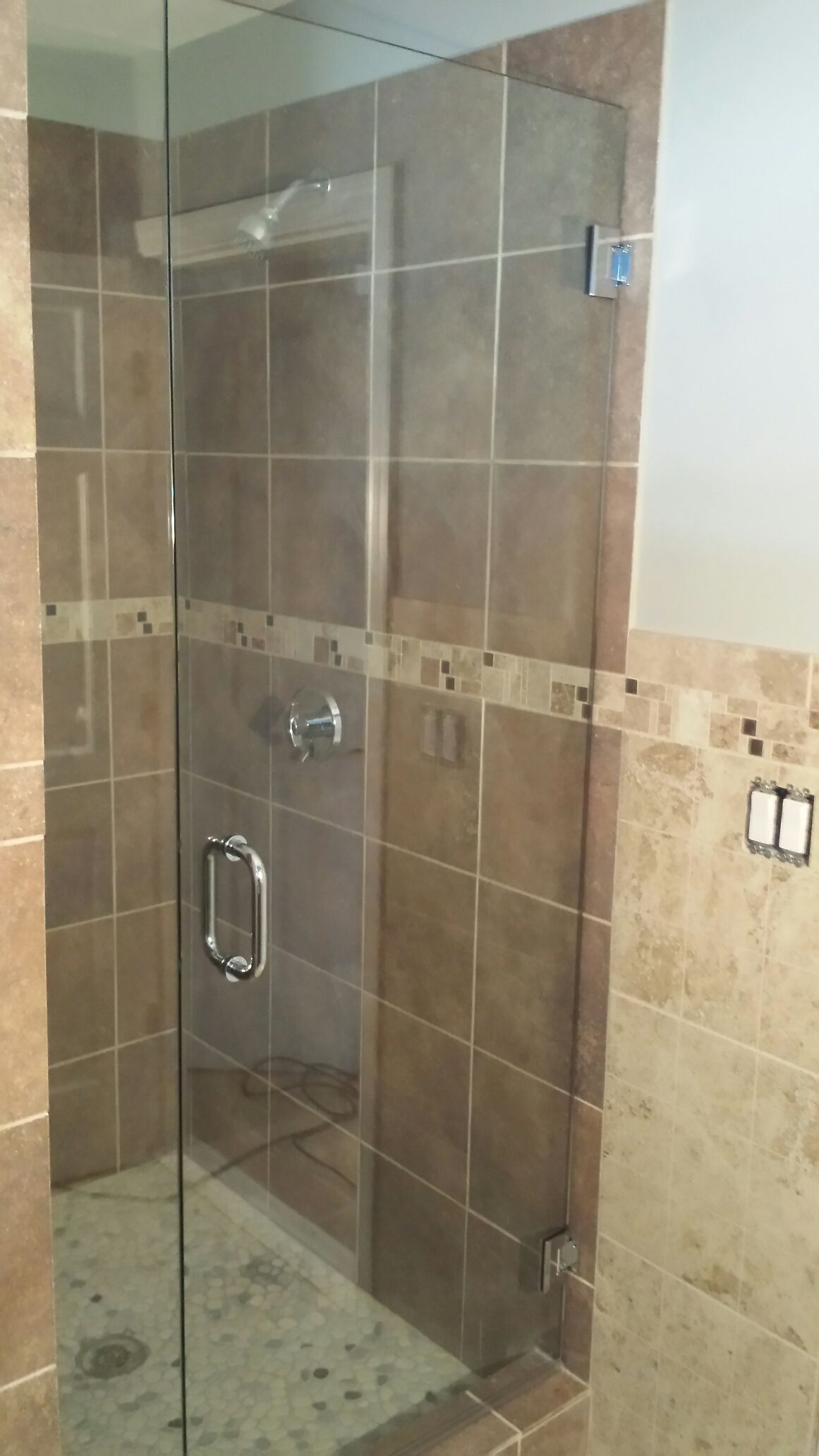 A bathroom with a walk in shower with a glass door.