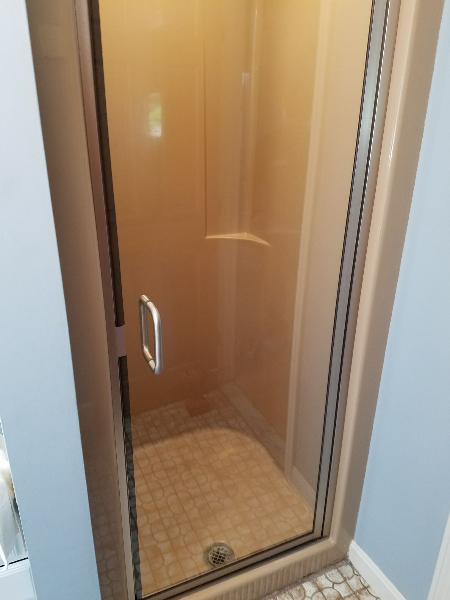 A bathroom with a walk in shower with a glass door