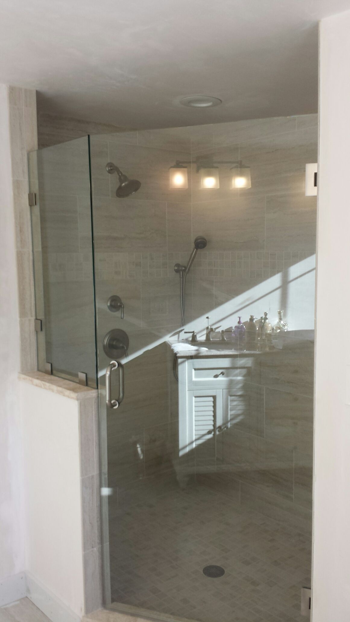 A bathroom with a glass shower door and a sink.