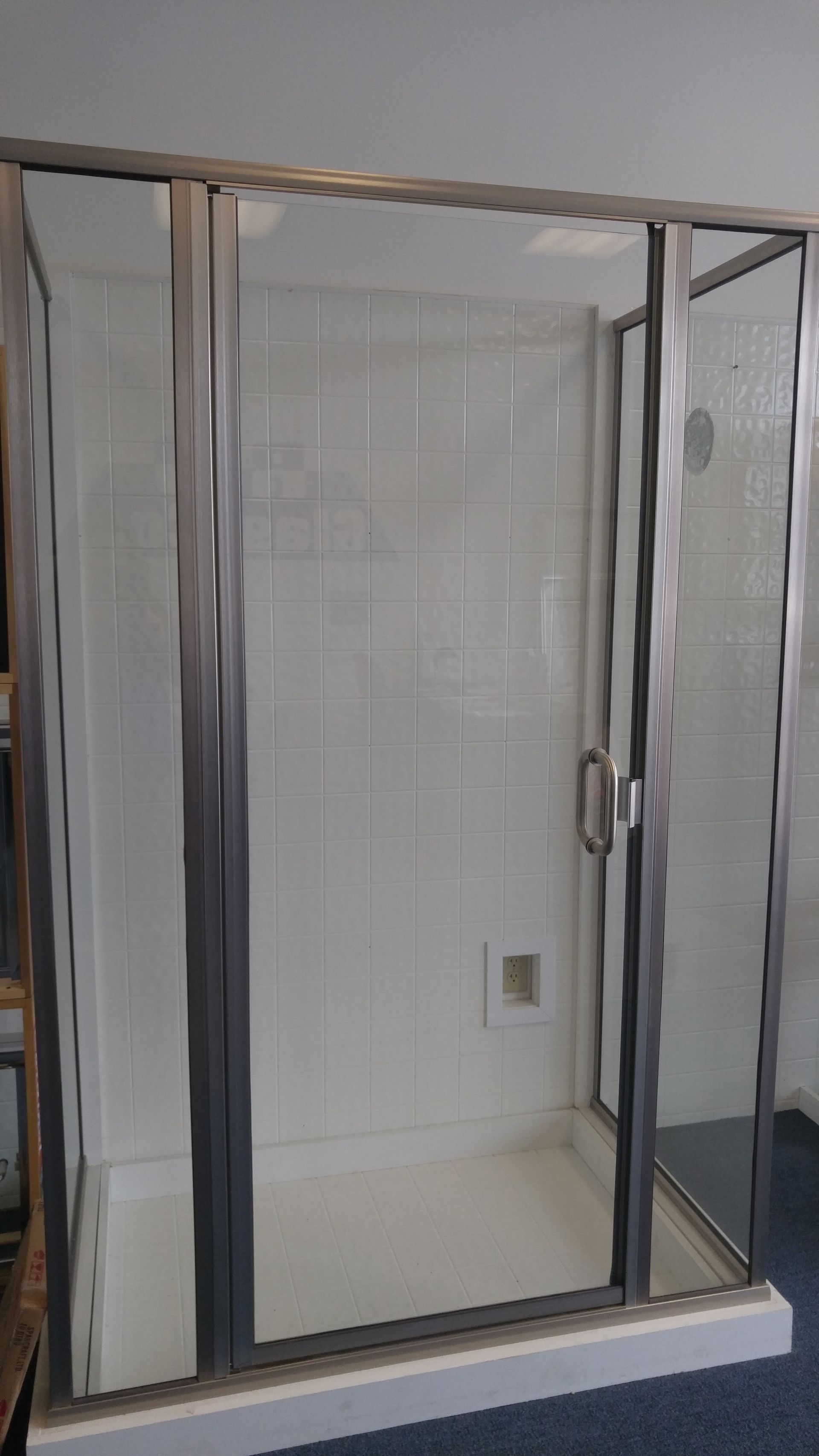 A shower stall with a stainless steel frame and glass doors in a bathroom.