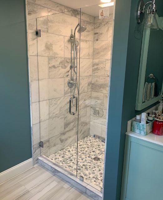 A bathroom with a walk in shower with a glass door.