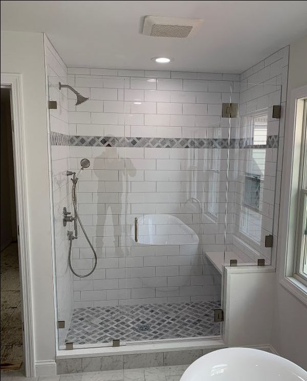 A bathroom with a walk in shower with a glass door.