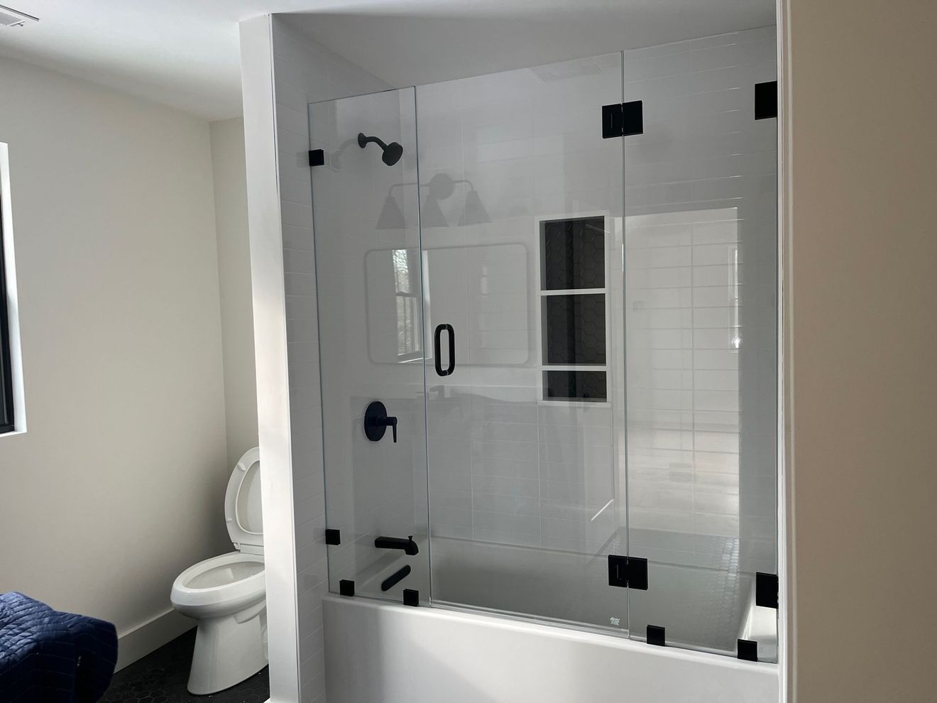 A bathroom with a toilet and a bathtub with a glass shower door.