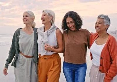 A group of women are standing next to each other on the beach.