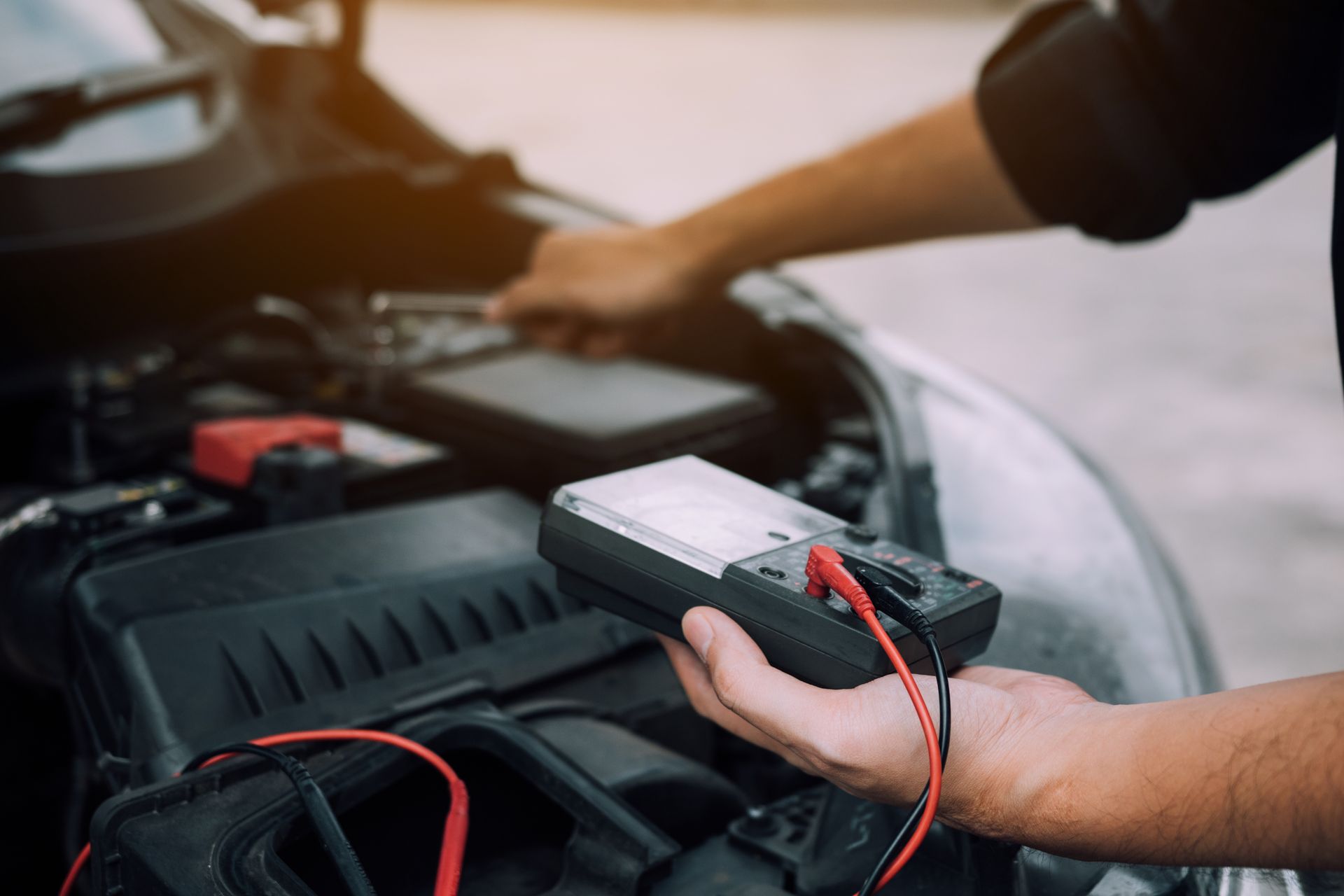 A man is using a multimeter to check the battery of a car.