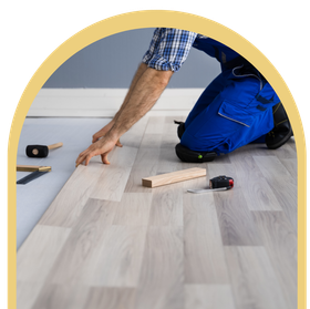 A man is kneeling down to install a wooden floor
