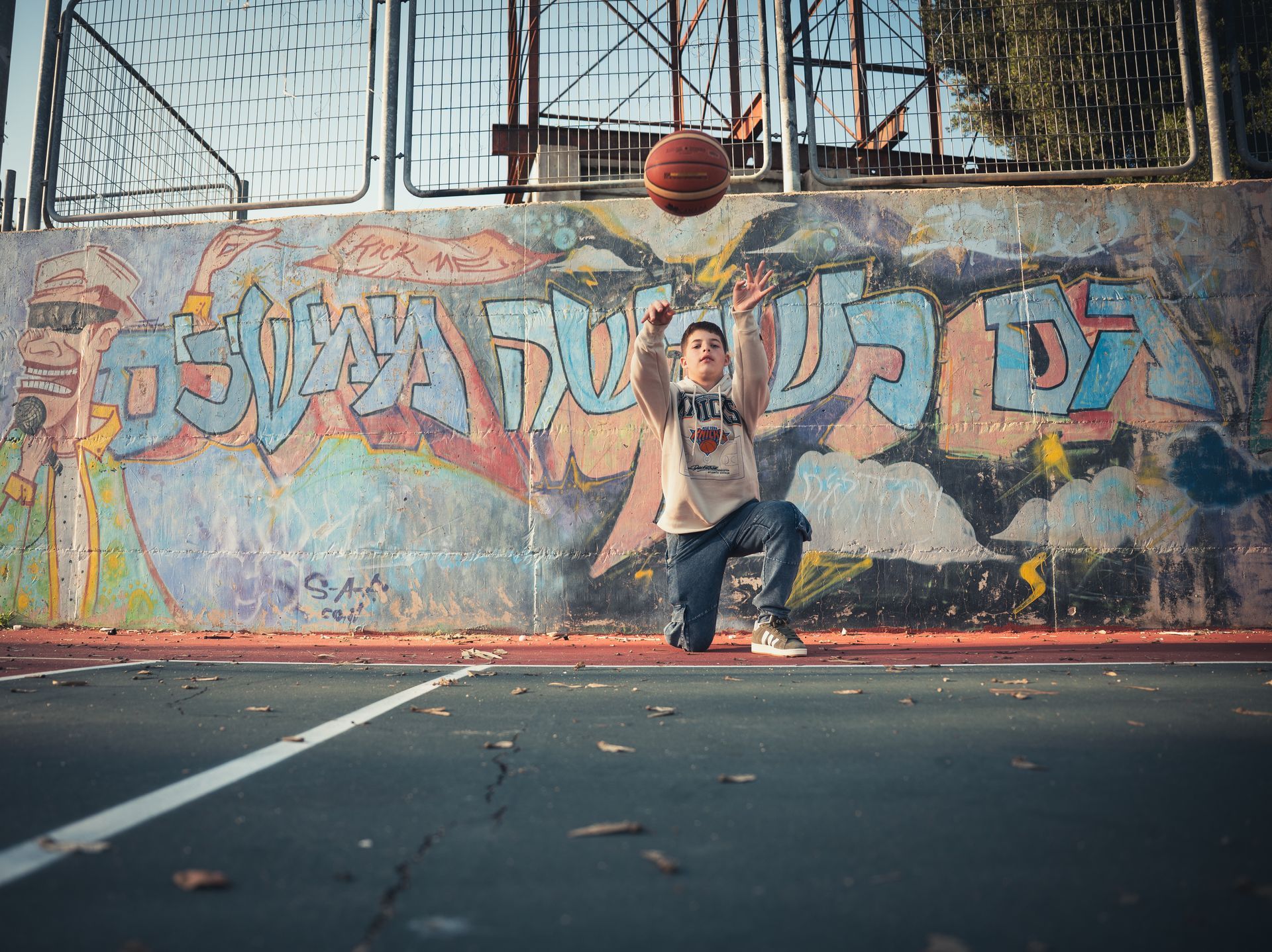 ילד בר מצווה משחק בכדור על רקע קיר מצוייר