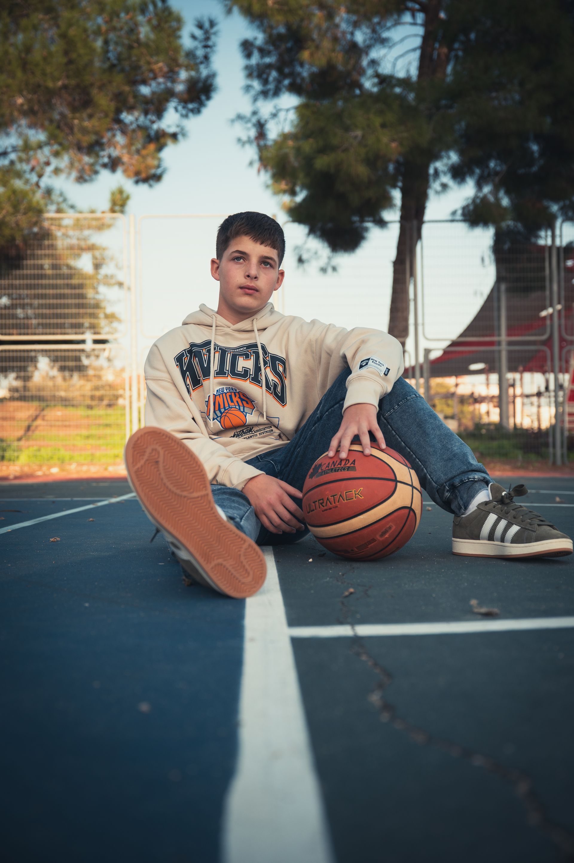 ילד בר מצווה עם כדורסל יושב במגרש