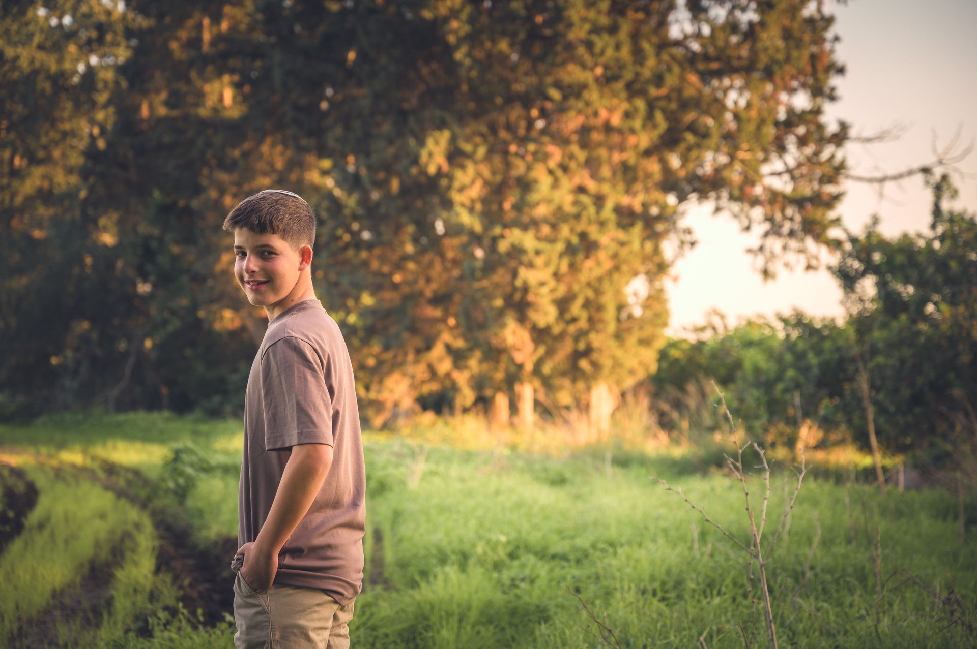 ילד בר מצווה מסתכל למצלמה בשדה ירוק