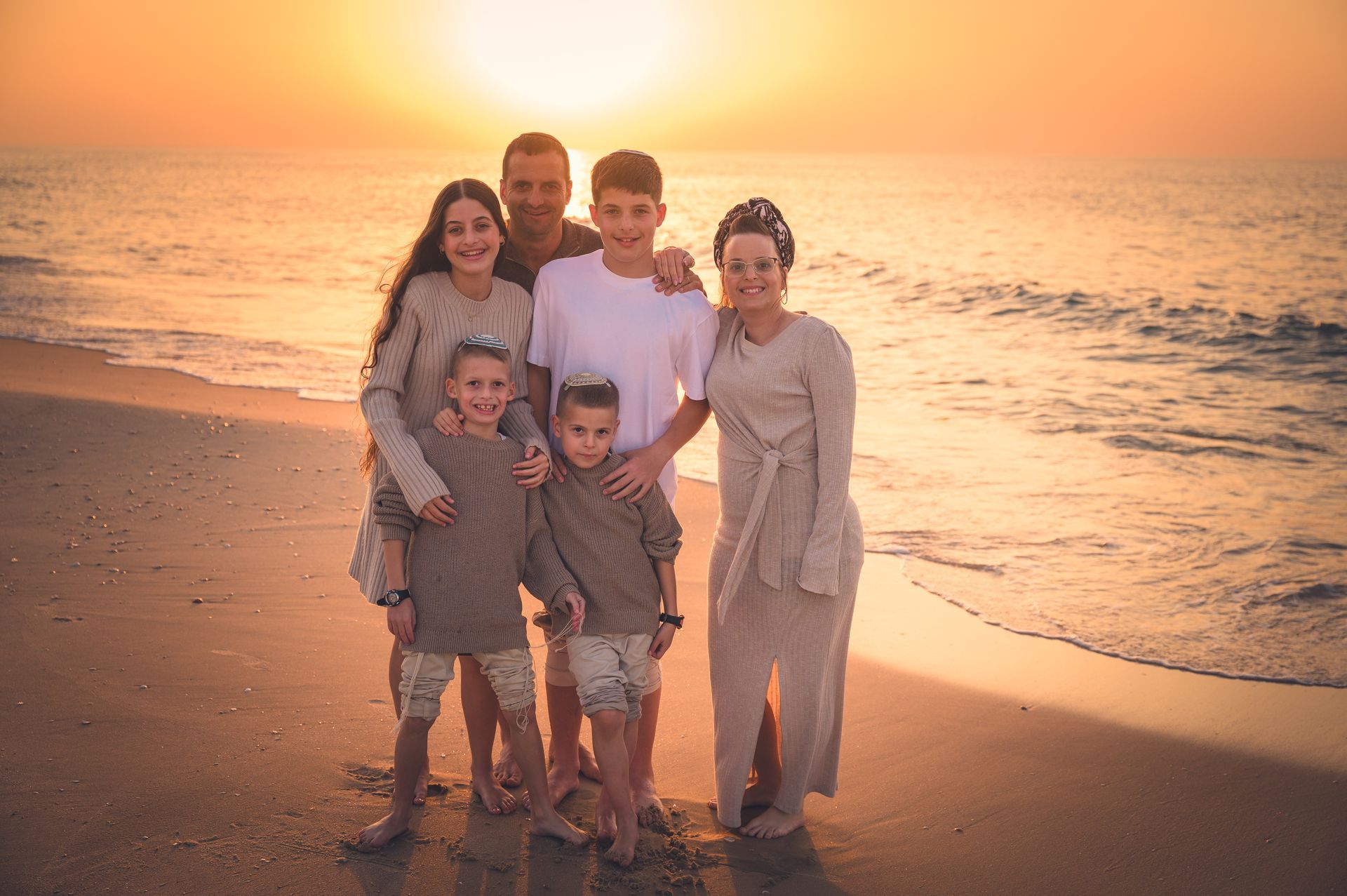 משפחה בת שש נפשות על רקע הים בשקיעה