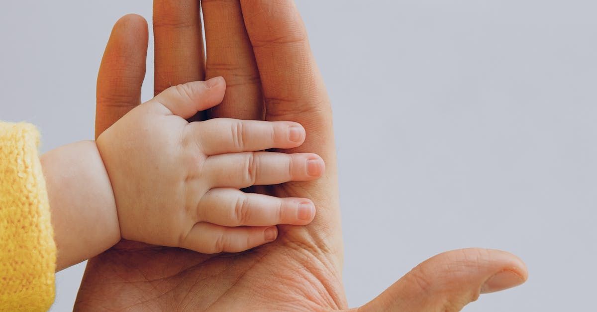 A person is holding a baby 's hand in their hand.