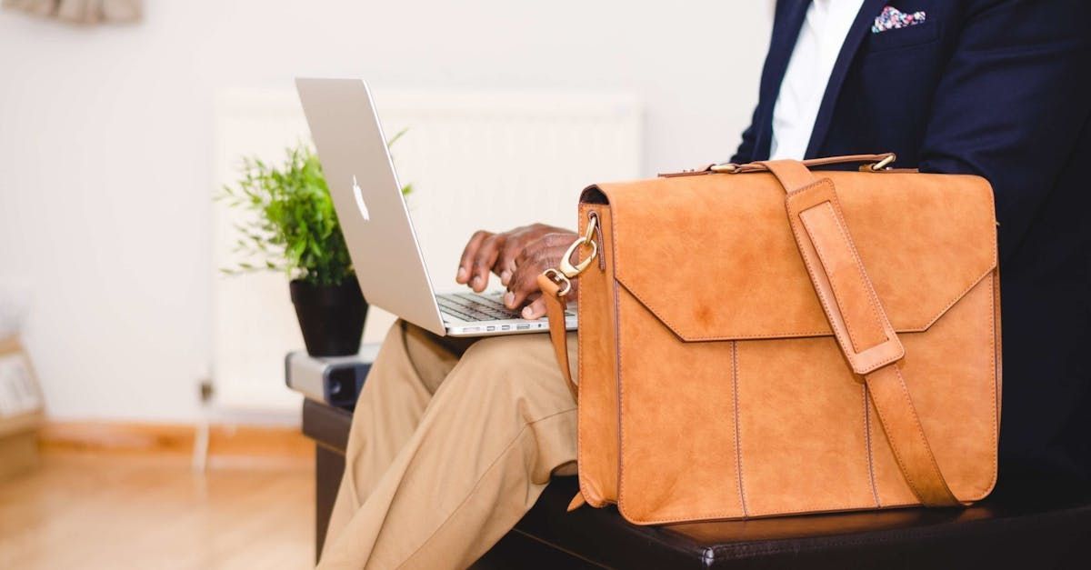 A man is sitting on a chair using a laptop and a briefcase.