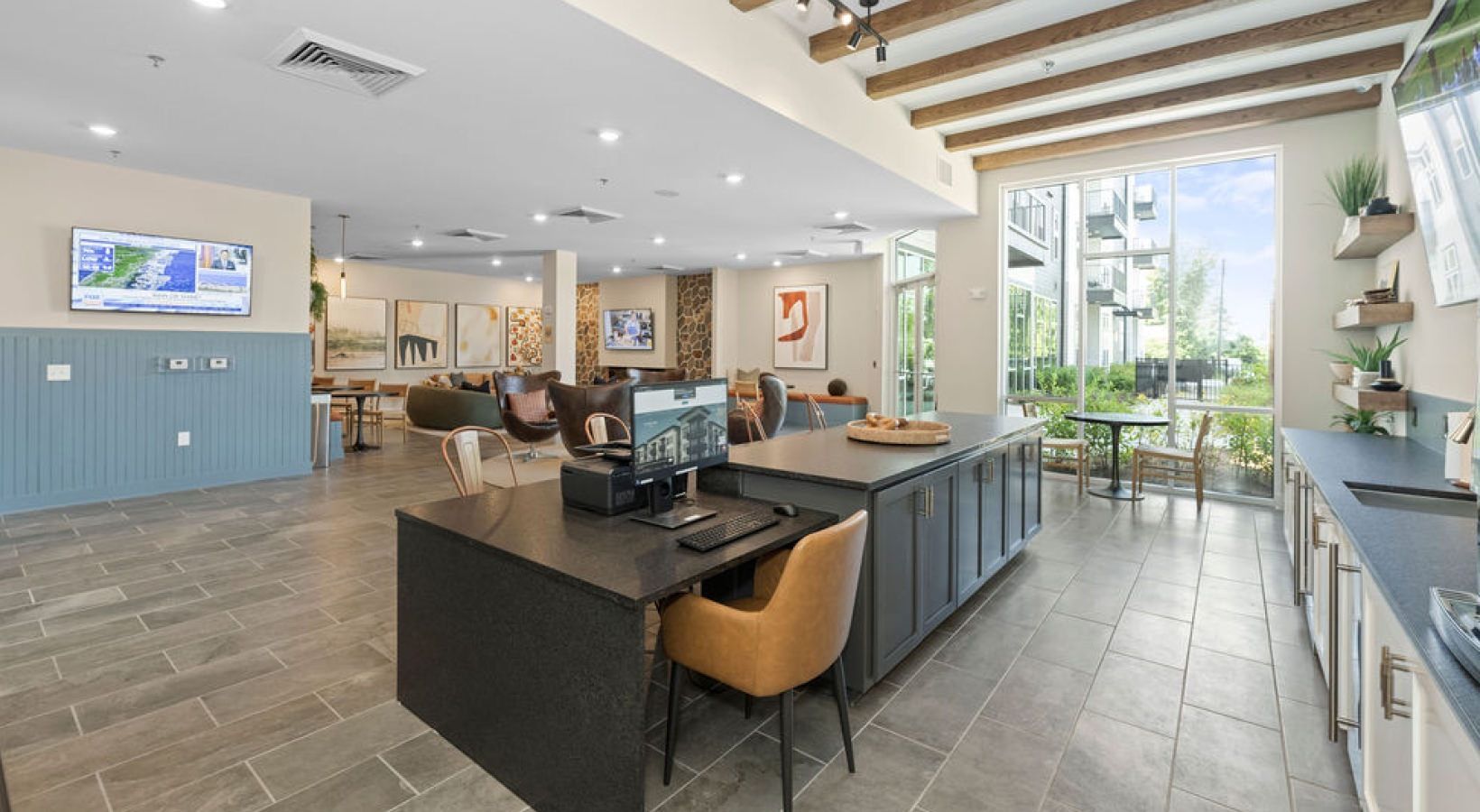 Spacious community clubhouse with a large island, lounge seating, and floor-to-ceiling windows.