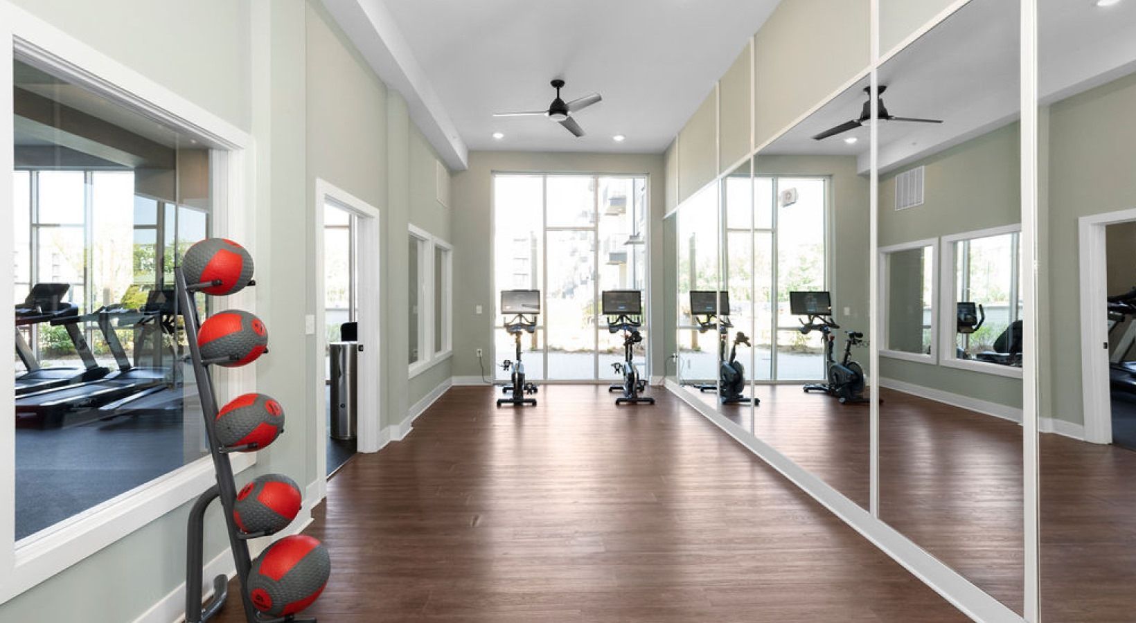 Fitness center with cardio bikes and treadmills, mirrored wall, and large windows.