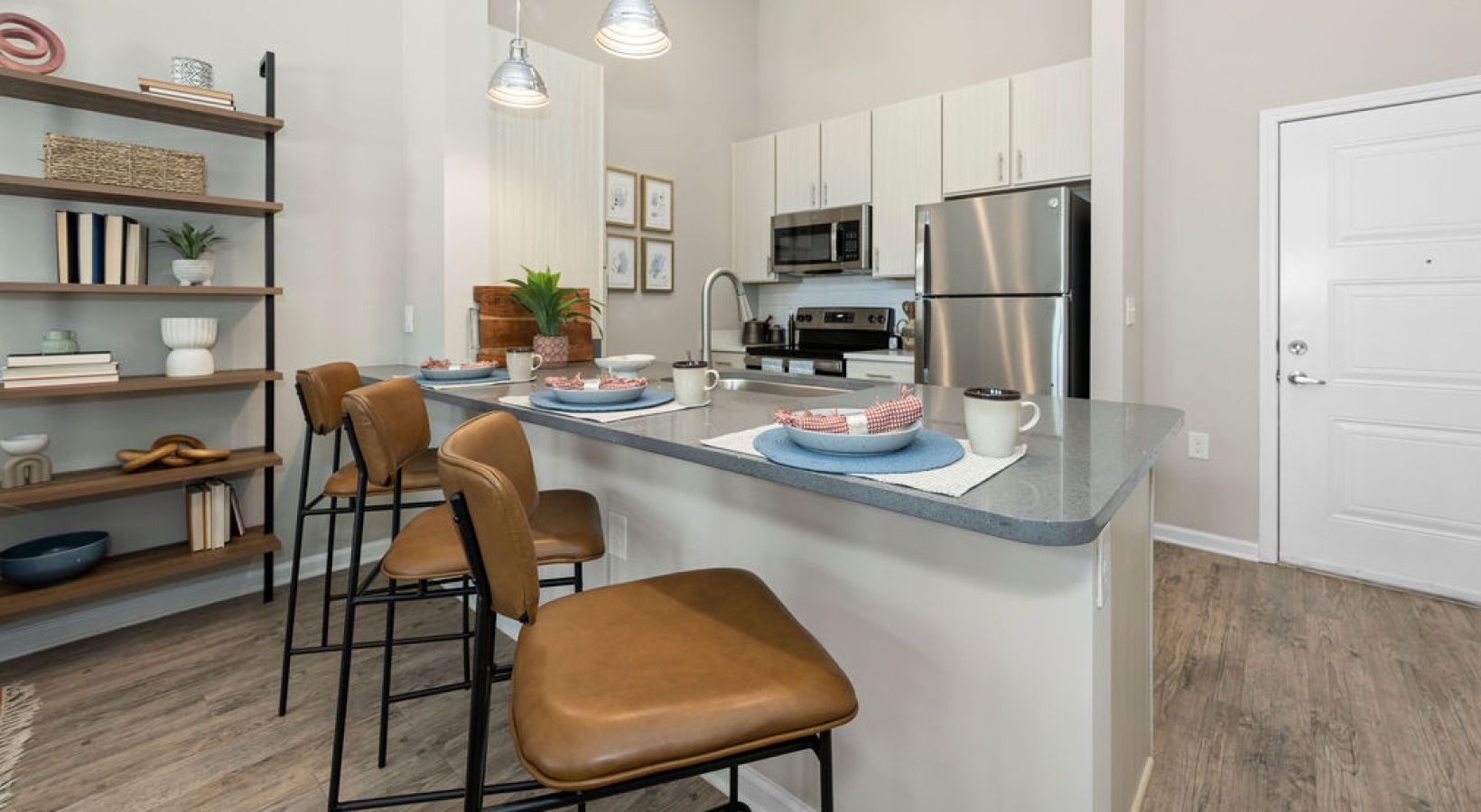Modern kitchen with island, stainless steel appliances, and wooden bar stools.
