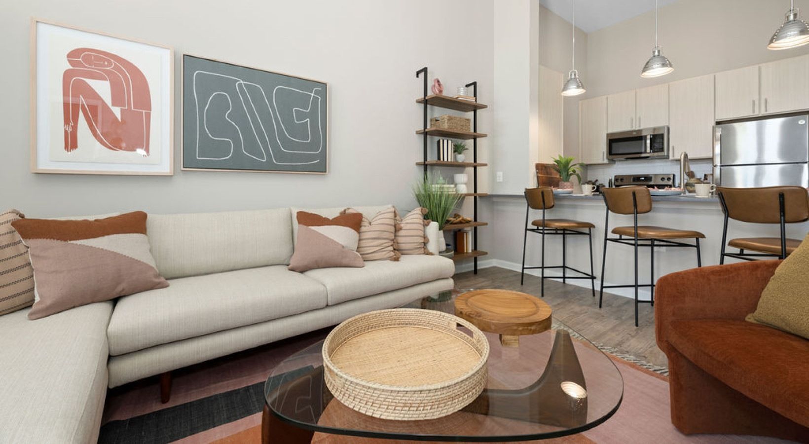 Open-concept living room with a beige sectional and a modern kitchen with bar stools.