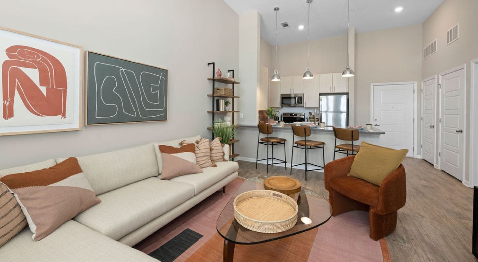 Open-concept living room and kitchen with sofa, chairs, and bar stools.