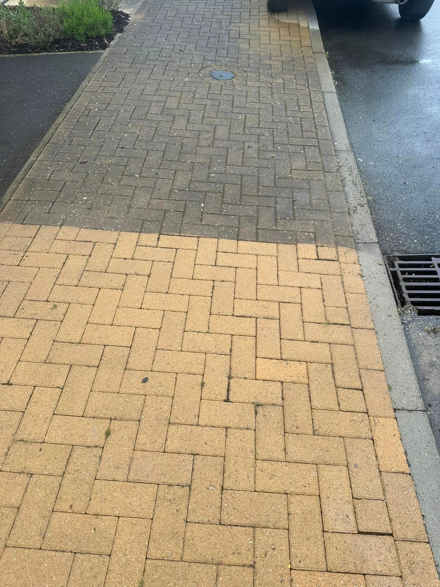 A brick sidewalk with a car parked on the side of it.
