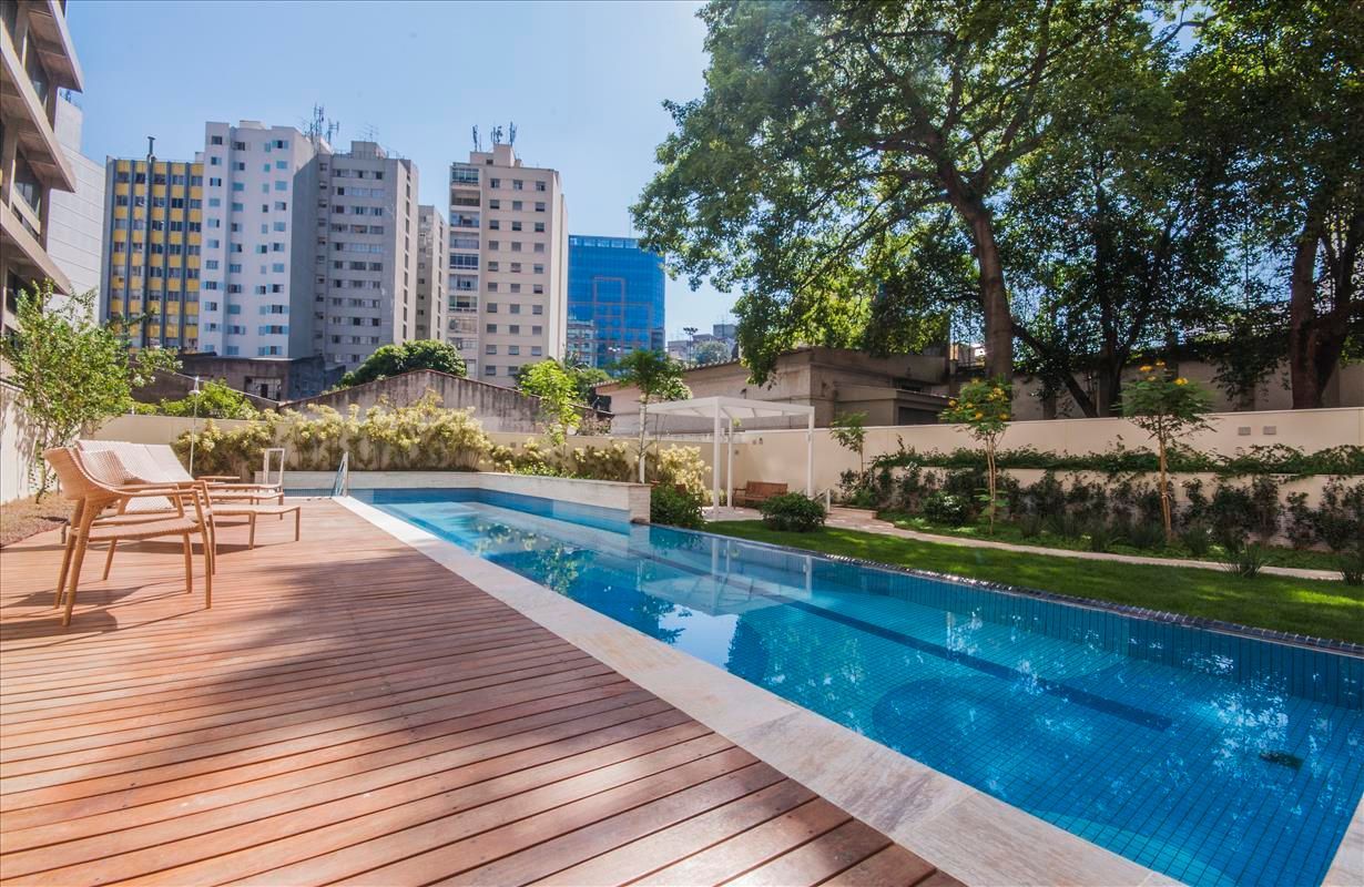 Piscina externa do eConfor Paulista, com deck em madeira, área verde bem cuidada e ambiente elegante para lazer e relaxamento em meio à cidade.