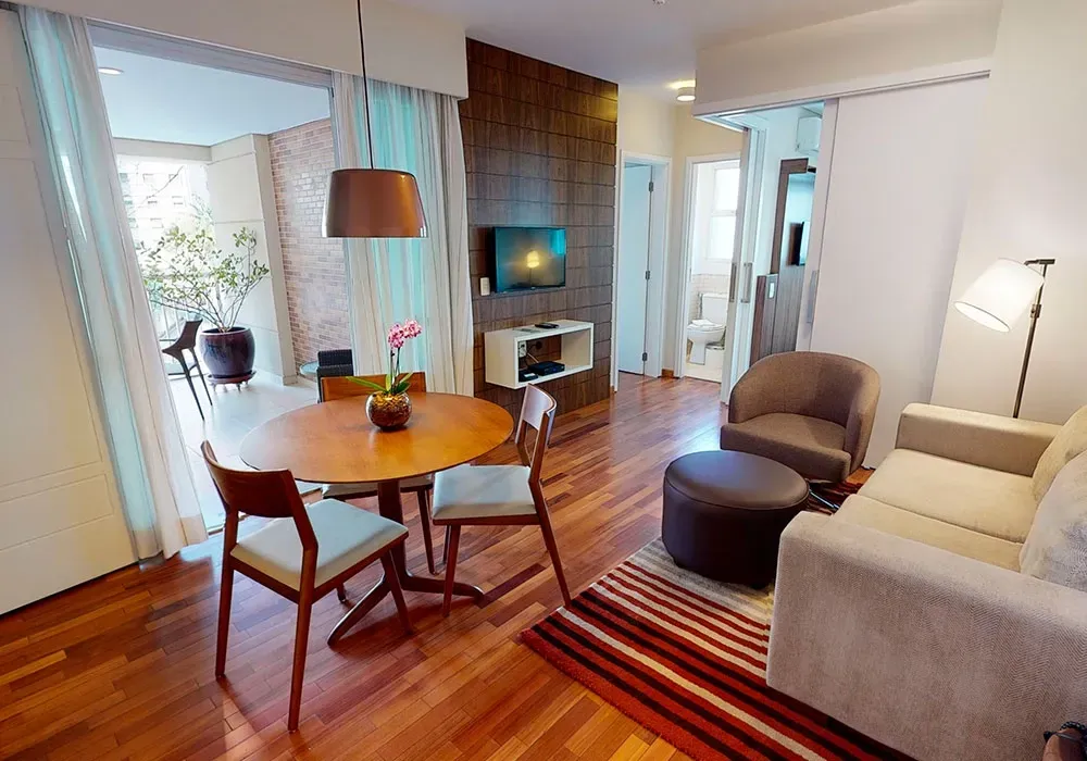 Uma banheira de hidromassagem branca em um deck de madeira ao lado de uma espreguiçadeira em uma varanda com vista para o horizonte da cidade.