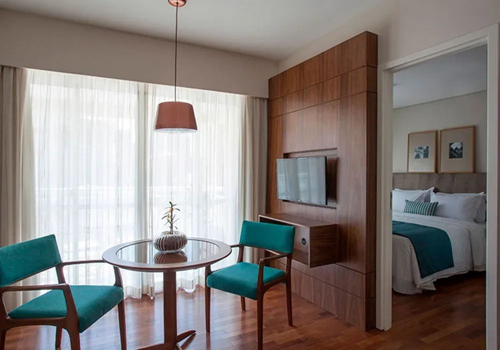 Um quarto de hotel com uma mesa, cadeiras e uma cama.