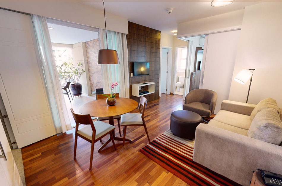 Uma sala de estar com um sofá, cadeiras, uma mesa e uma televisão.