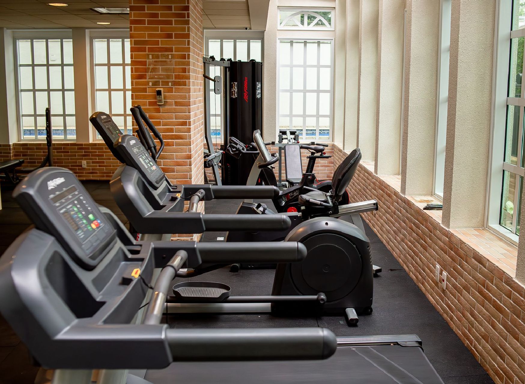 Uma fileira de esteiras estão alinhadas em uma academia.