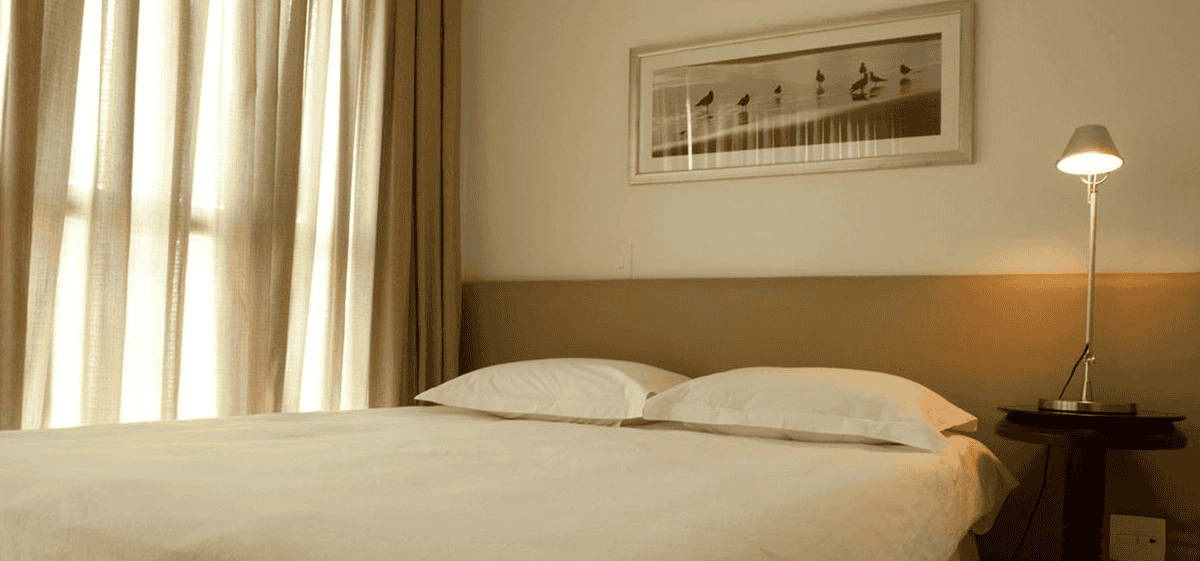 Quarto do eConfor Jardins com cama ampla, iluminação aconchegante e decoração sofisticada em estilo alto padrão.