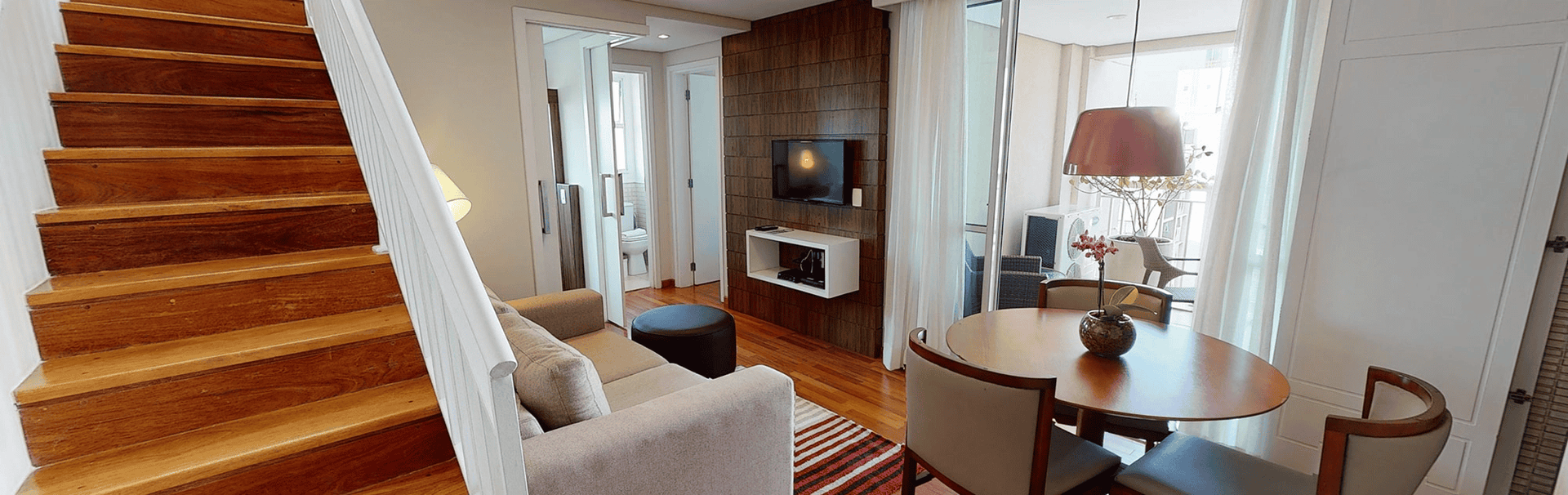 Terraço amplo e bem decorado do eConfor Paulista, com área de estar, deck com jacuzzi e integração ao quarto em um ambiente exclusivo e confortável.