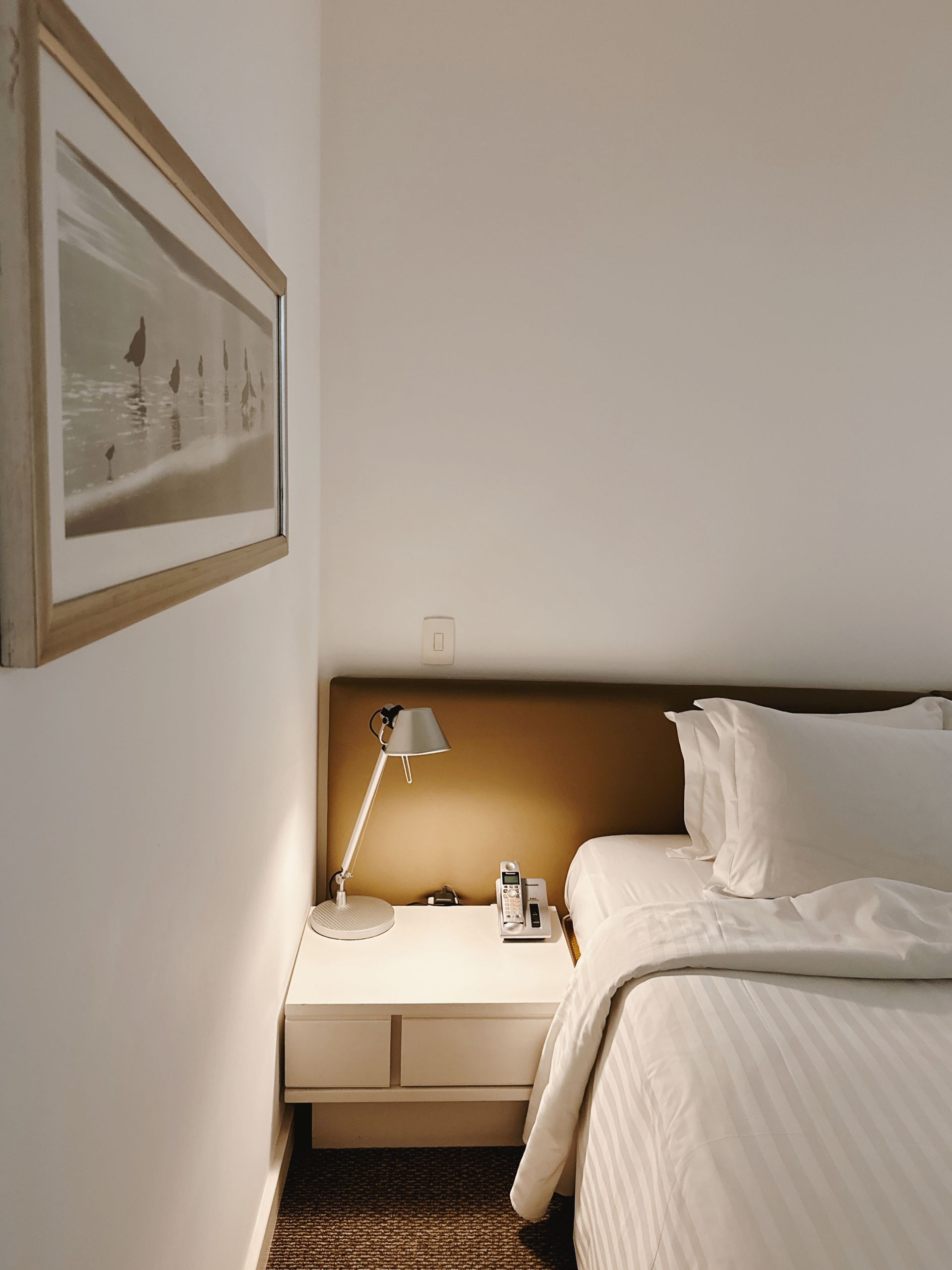Quarto aconchegante do eConfor Paulista, com décor minimalista, enxoval impecável e iluminação suave que cria um ambiente refinado e tranquilo.