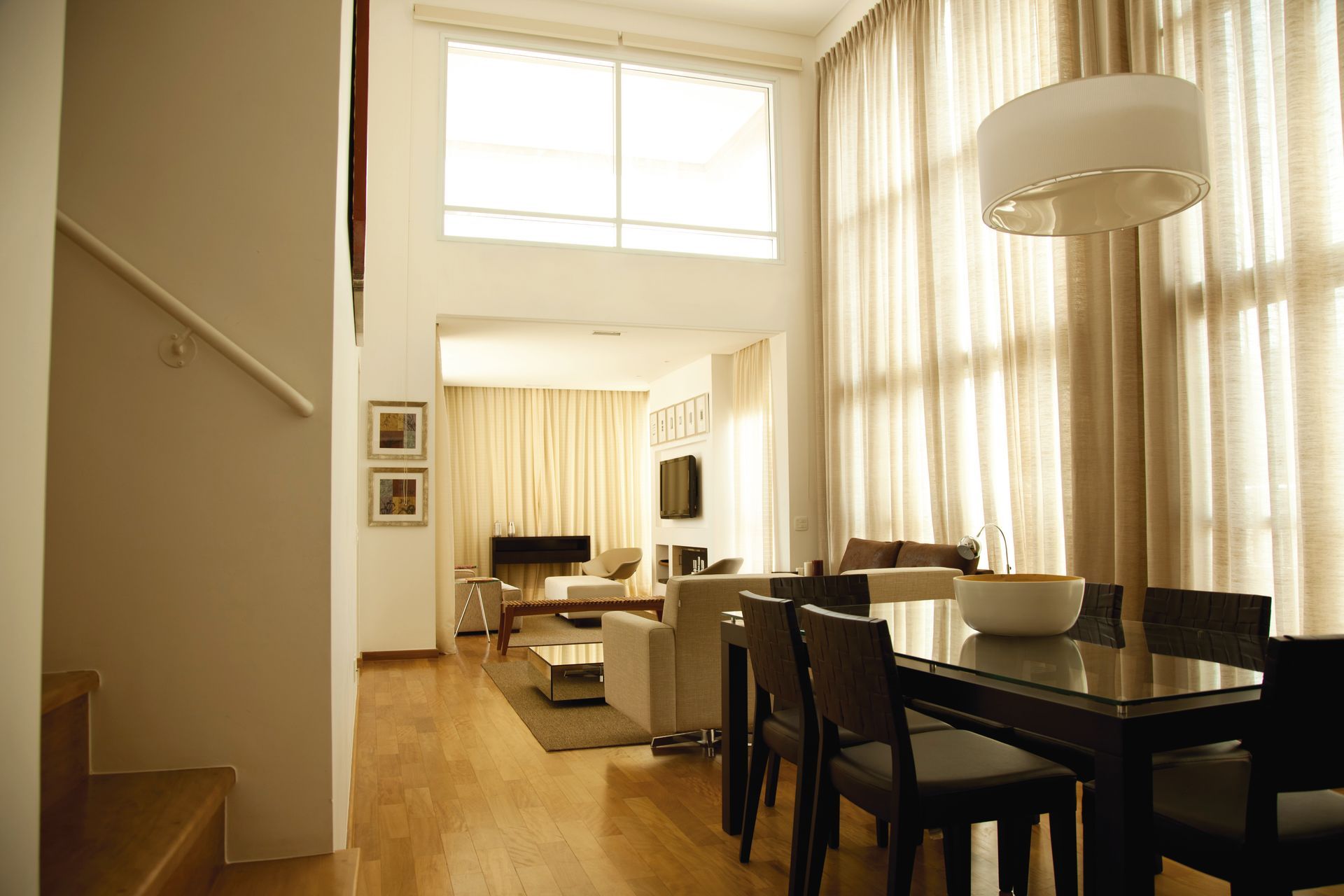 Sala integrada do eConfor Jardins com pé-direito alto, janelas amplas, decoração elegante e ambiente de alto padrão.