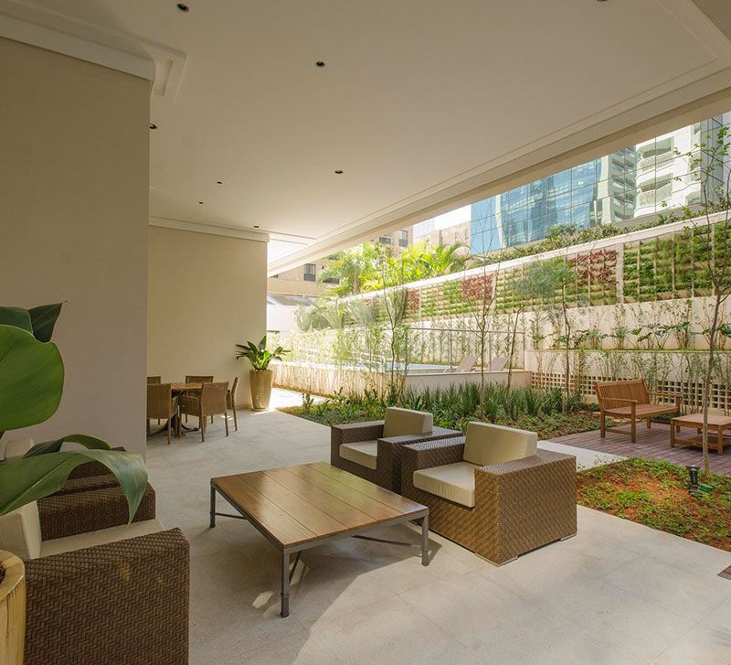 Área externa elegante do eConfor Vila Olímpia, com mobiliário sofisticado, paisagismo cuidadoso e ambiente de alto padrão para relaxar.