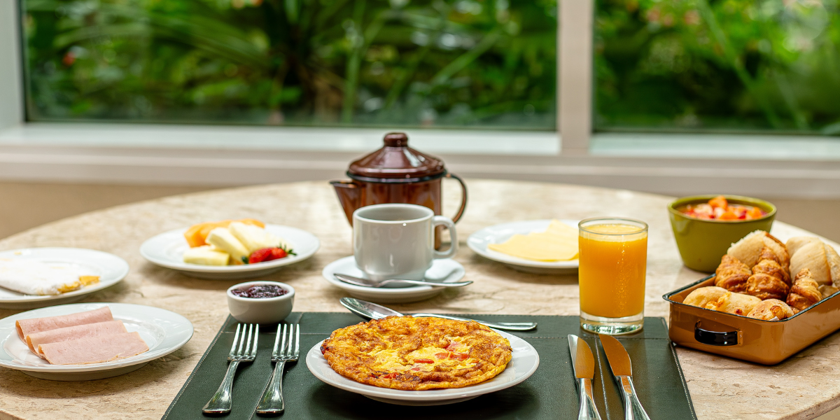 Uma mesa coberta com pratos de comida e um copo de suco de laranja.