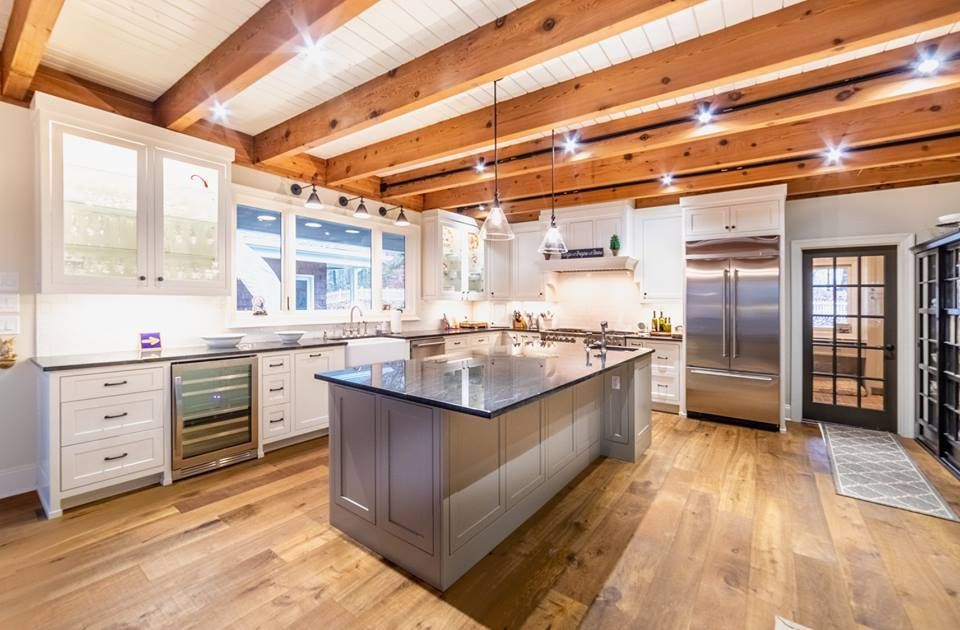 A modern kitchen with wood floors, white cabinets, and a large island.