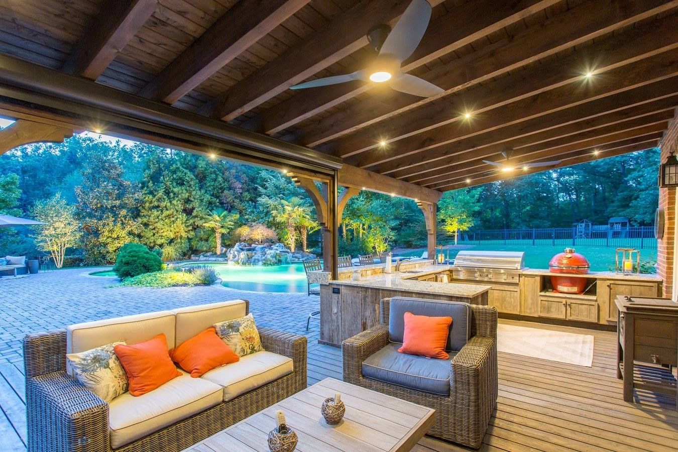 Outdoor patio with seating, kitchen, and pool. Overhead wood beams, recessed lights, and a ceiling fan.