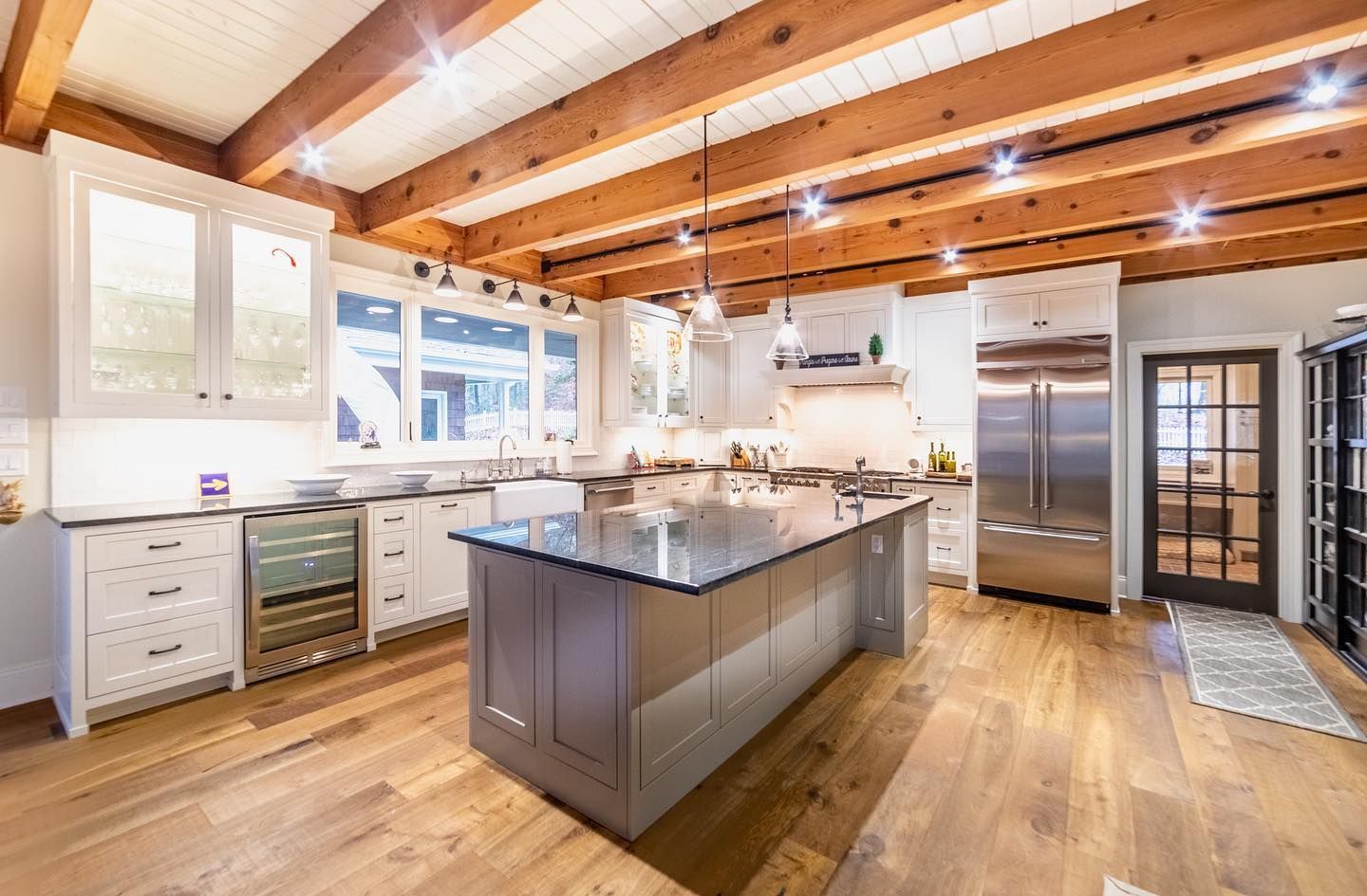 Spacious kitchen with wood beams, stainless steel appliances, an island, and light cabinets.