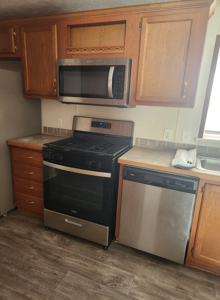 Kitchen with stainless steel appliances, wooden cabinets, and a gas range.
