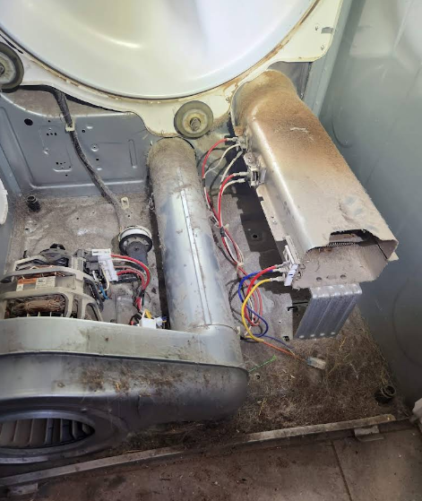 Interior of a dryer with exposed components; a motor, heating element, and vents are visible.