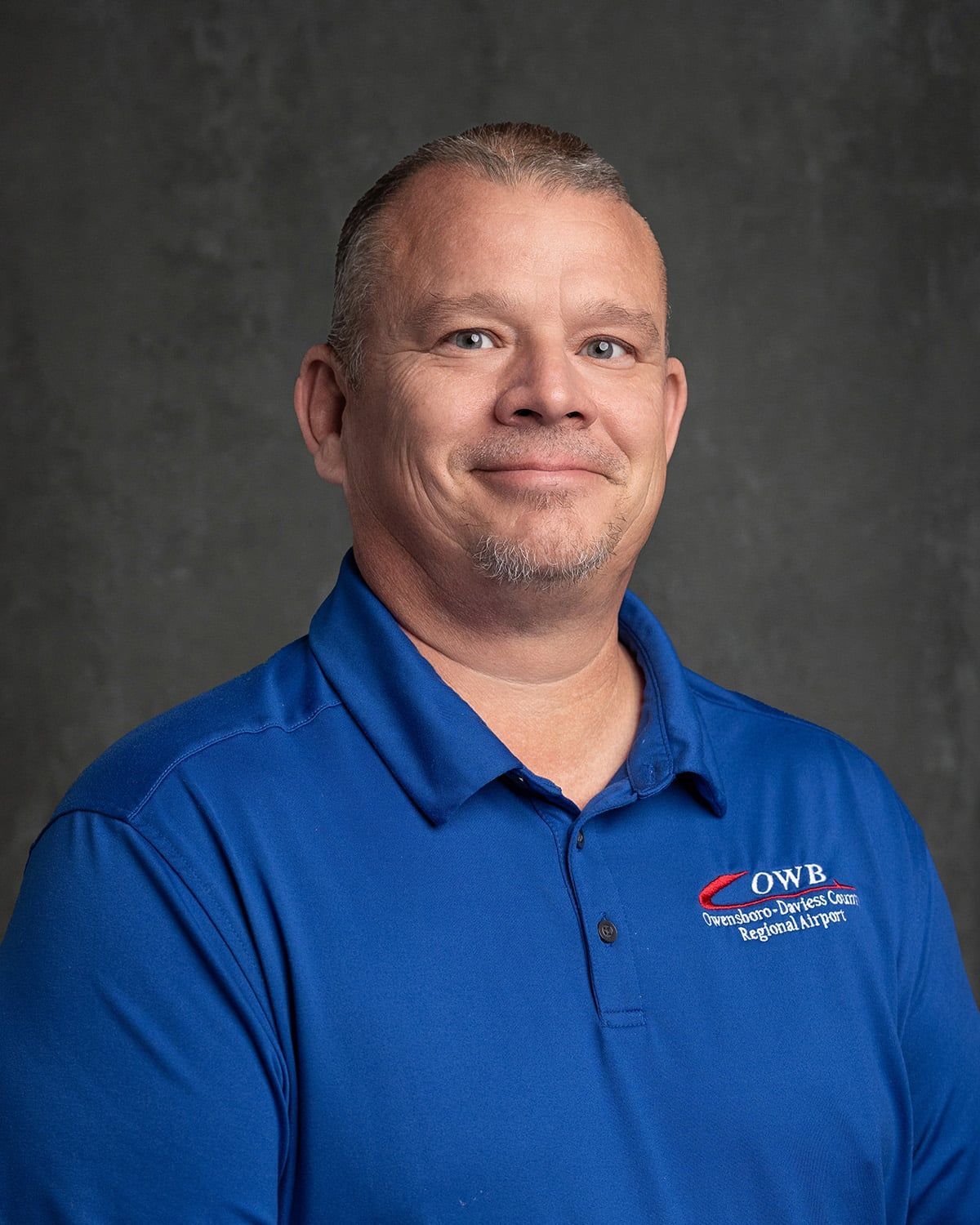 A man in a blue shirt is smiling for the camera.