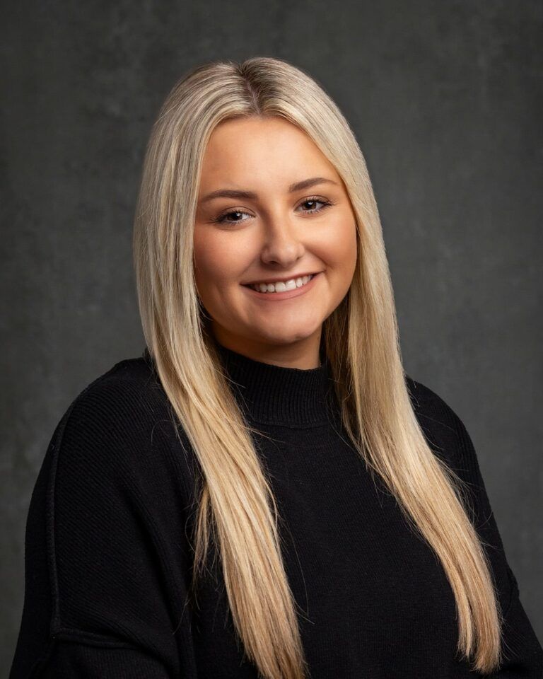 The woman is wearing a black sweater and smiling for the camera.