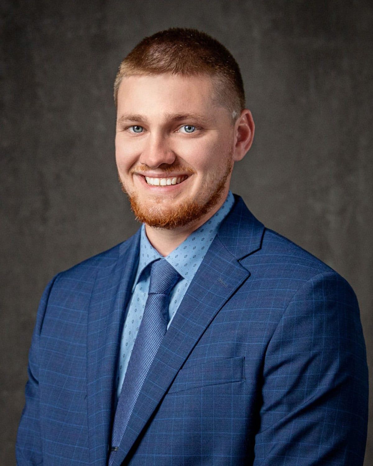 A man in a blue suit and tie is smiling for the camera.