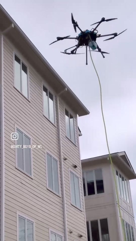 A drone is flying over a building with a rope attached to it.