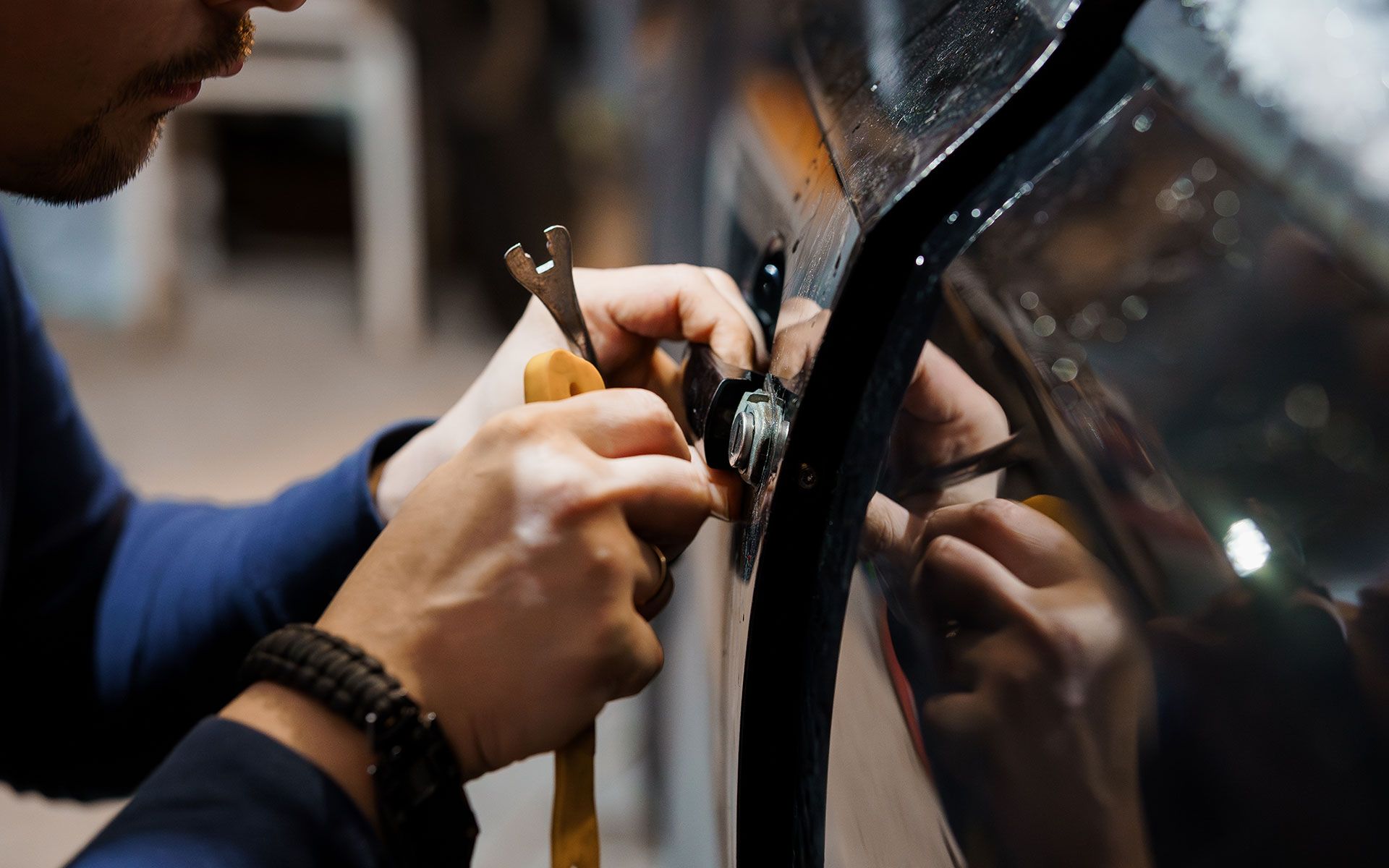 Person using tools to repair a car door.