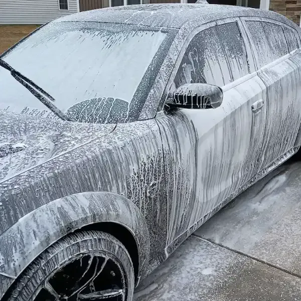 Black car covered in white foam during a car wash.
