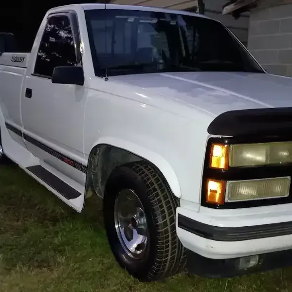 White Chevrolet pickup truck parked on grass.