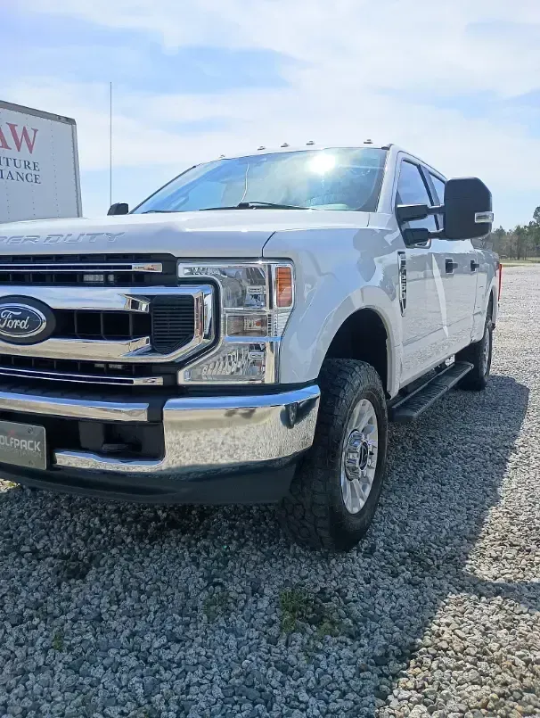 White Ford pickup truck parked on gravel, sunny day.