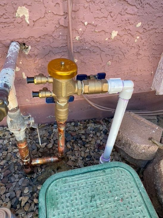 Water valve assembly with brass components and a green utility box.
