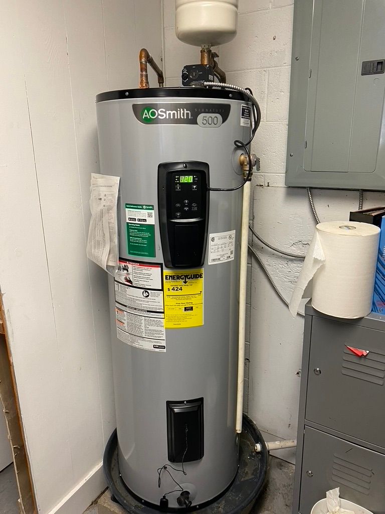 A.O. Smith electric water heater in a utility room, with attached control panel, pipes, and labels.